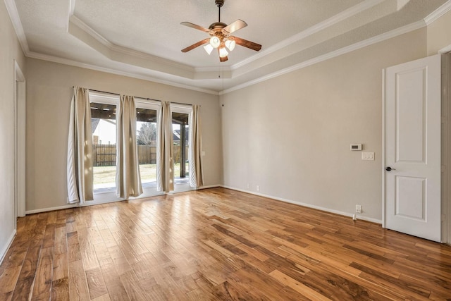 spare room featuring ceiling fan, ornamental molding, a raised ceiling, and wood-type flooring