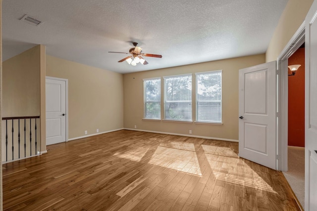 unfurnished room with ceiling fan, light hardwood / wood-style floors, and a textured ceiling