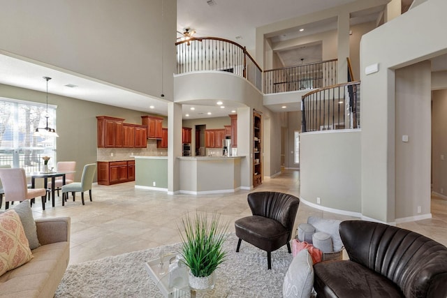 living room with a towering ceiling and ceiling fan with notable chandelier