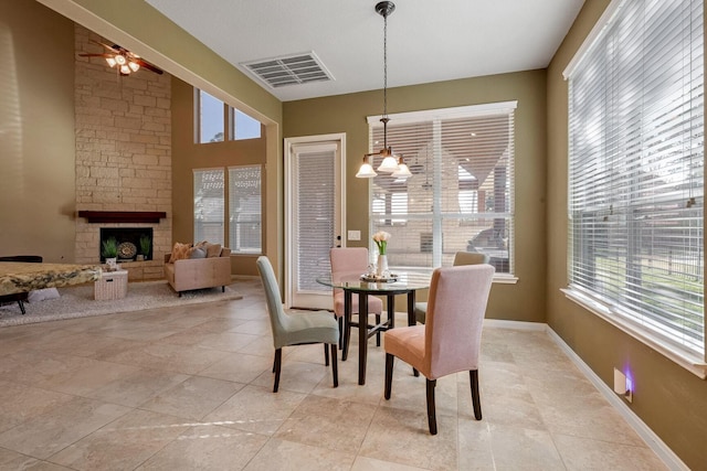 tiled dining area with ceiling fan, a wealth of natural light, and a fireplace