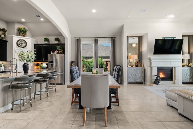 dining room featuring sink, vaulted ceiling, and light tile patterned flooring