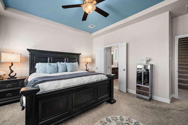 bedroom with ceiling fan, light carpet, and ensuite bath