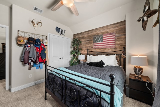 carpeted bedroom featuring a closet, vaulted ceiling, ceiling fan, and wood walls