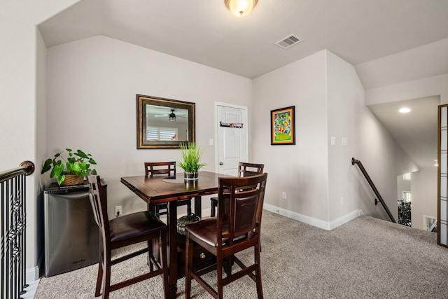 carpeted dining area featuring vaulted ceiling