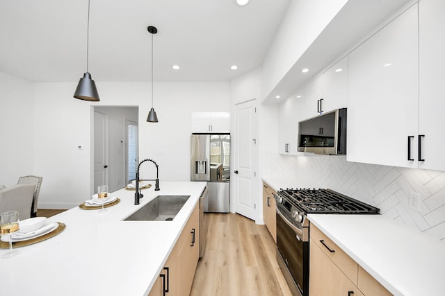 kitchen featuring appliances with stainless steel finishes, decorative light fixtures, white cabinetry, sink, and decorative backsplash