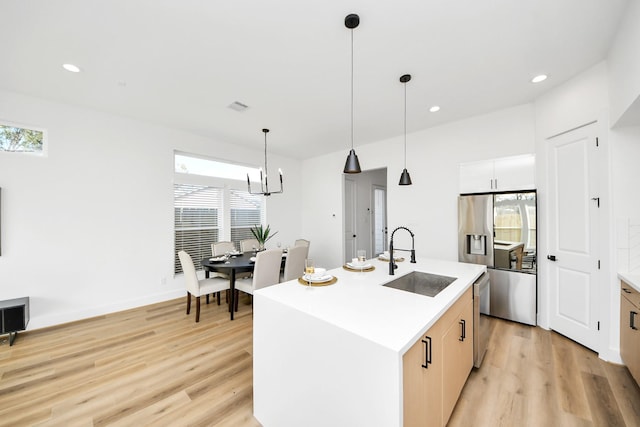 kitchen with pendant lighting, sink, light hardwood / wood-style flooring, dishwasher, and a center island with sink