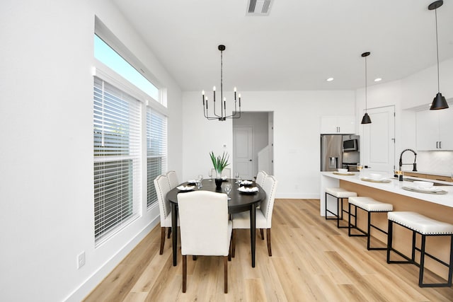 dining space featuring a notable chandelier, sink, and light wood-type flooring