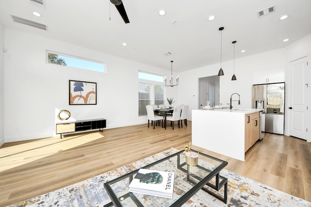 living room with sink, a notable chandelier, and light hardwood / wood-style flooring