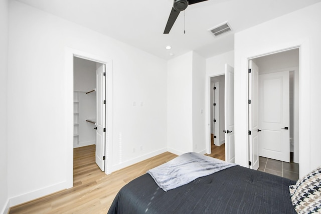 bedroom featuring hardwood / wood-style flooring, a walk in closet, ceiling fan, and a closet