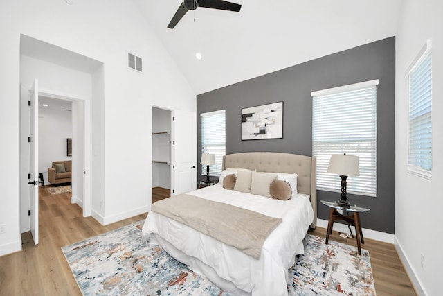 bedroom featuring multiple windows, a walk in closet, ceiling fan, and light hardwood / wood-style floors