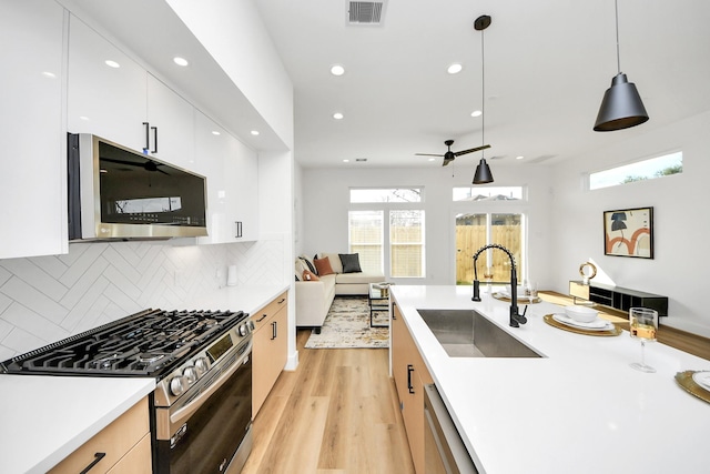 kitchen with sink, white cabinetry, tasteful backsplash, hanging light fixtures, and stainless steel appliances