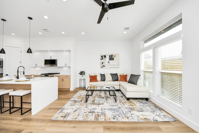 living room featuring ceiling fan, light hardwood / wood-style floors, and sink