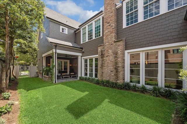 rear view of property featuring a yard and a patio area