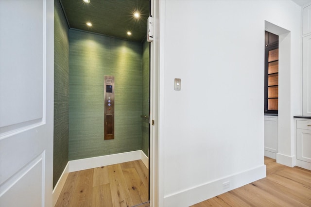 hallway with elevator and light hardwood / wood-style flooring