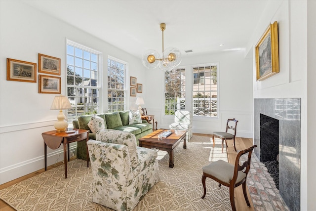 interior space with a notable chandelier, a healthy amount of sunlight, a high end fireplace, and light wood-type flooring