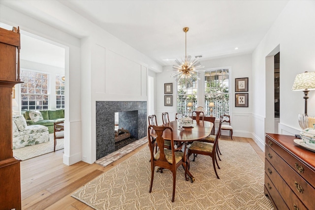 dining area featuring a notable chandelier, light hardwood / wood-style floors, and a premium fireplace