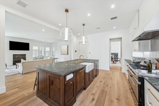 kitchen featuring white cabinetry, sink, custom range hood, and pendant lighting