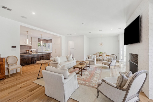 living room featuring a brick fireplace and light wood-type flooring