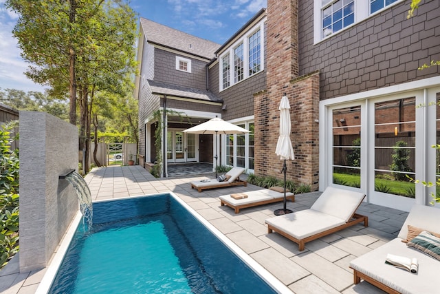 view of swimming pool with pool water feature and a patio