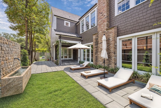 rear view of house with a patio and a lawn