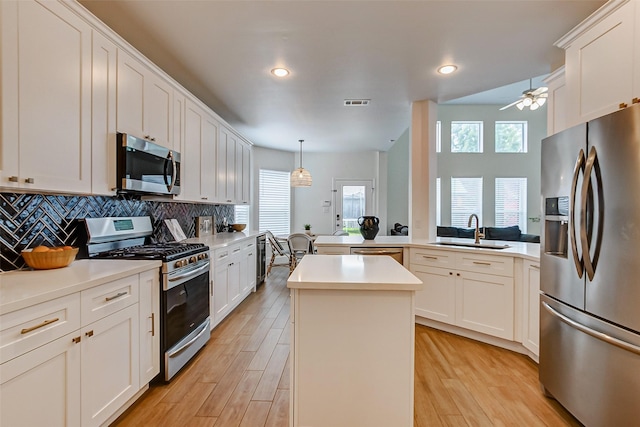 kitchen with sink, tasteful backsplash, decorative light fixtures, appliances with stainless steel finishes, and kitchen peninsula