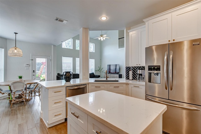 kitchen with white cabinetry, appliances with stainless steel finishes, a center island, and decorative backsplash