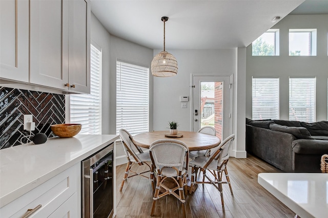 dining room featuring a healthy amount of sunlight, beverage cooler, and light hardwood / wood-style floors