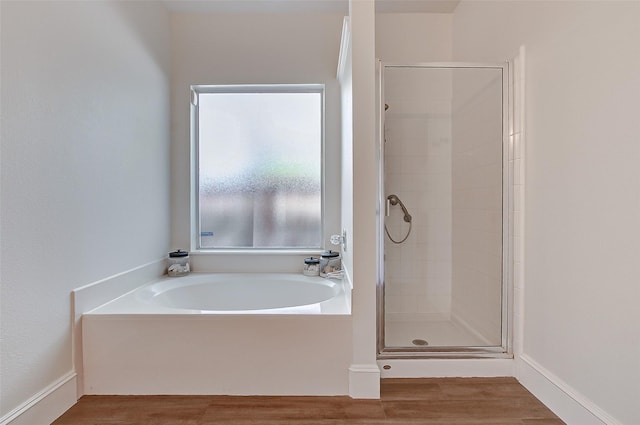 bathroom featuring plus walk in shower and hardwood / wood-style floors