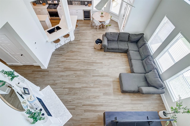 living room with wine cooler, a towering ceiling, and light hardwood / wood-style flooring