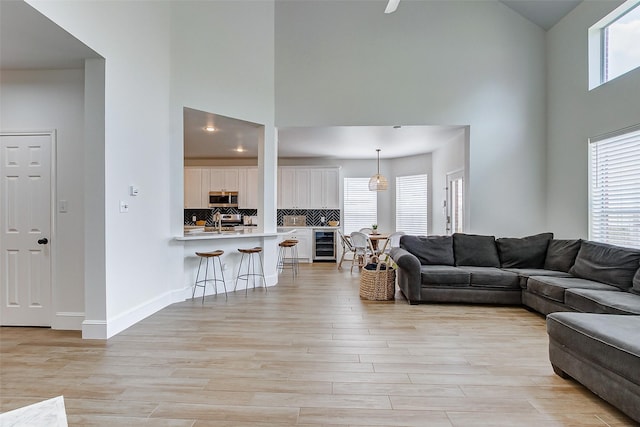 living room with light hardwood / wood-style floors, beverage cooler, and a high ceiling