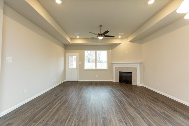 unfurnished living room with a tile fireplace, dark wood-type flooring, and ceiling fan