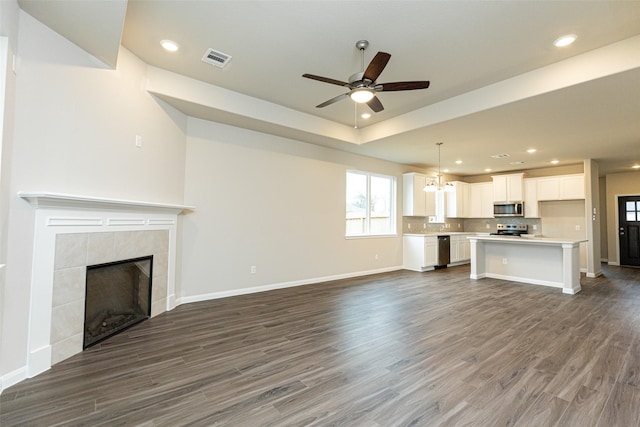 unfurnished living room with ceiling fan, a fireplace, and dark hardwood / wood-style flooring