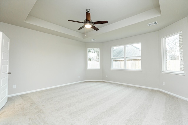 carpeted empty room featuring ceiling fan and a tray ceiling