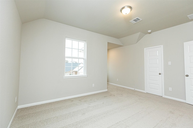 spare room featuring vaulted ceiling and light carpet