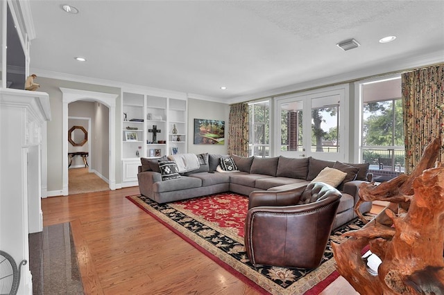 living room with ornamental molding, hardwood / wood-style floors, and built in shelves