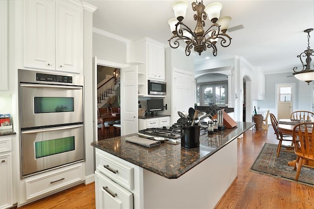 kitchen featuring ornamental molding, appliances with stainless steel finishes, decorative light fixtures, and white cabinets