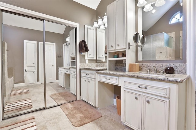 bathroom featuring vanity, tile patterned flooring, and vaulted ceiling