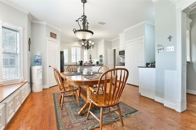 dining area with an inviting chandelier, crown molding, and light wood-type flooring