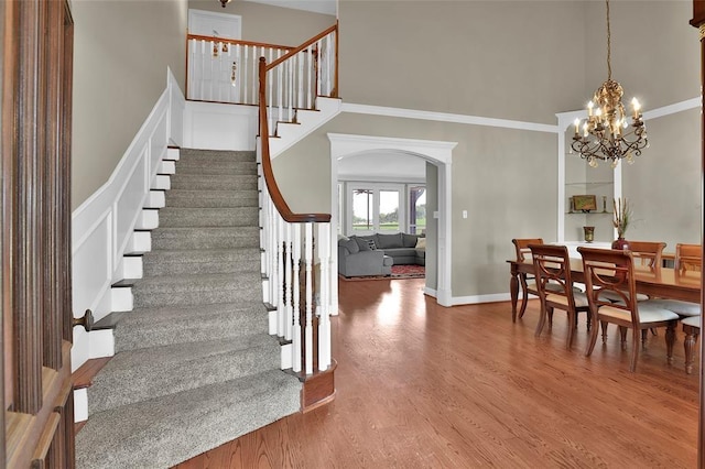 stairway featuring hardwood / wood-style floors, a towering ceiling, and a notable chandelier