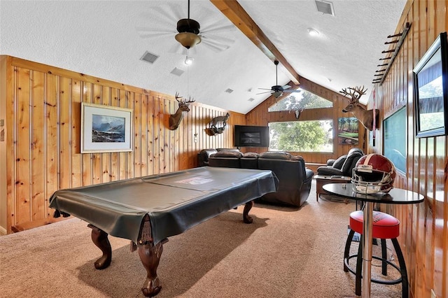 recreation room with ceiling fan, wooden walls, carpet floors, lofted ceiling with beams, and a textured ceiling