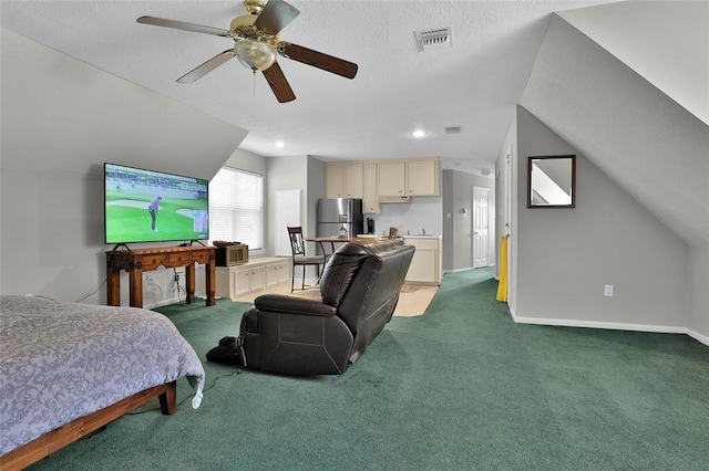 carpeted bedroom featuring a textured ceiling, vaulted ceiling, stainless steel refrigerator, and ceiling fan