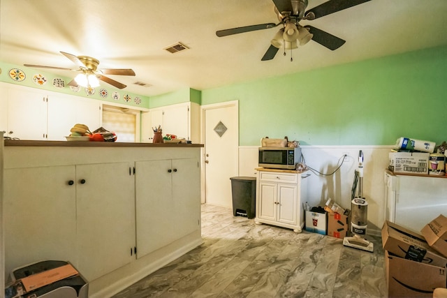 kitchen featuring ceiling fan and white cabinets