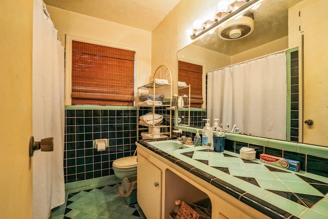 bathroom featuring vanity, tile walls, and toilet