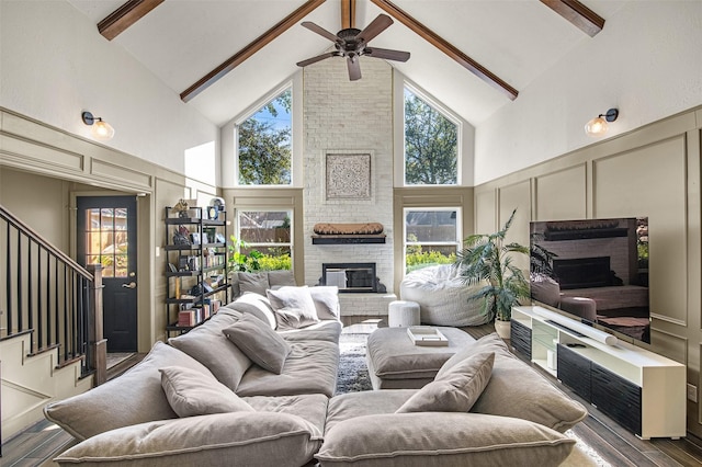 living room with hardwood / wood-style floors, high vaulted ceiling, a fireplace, ceiling fan, and beam ceiling