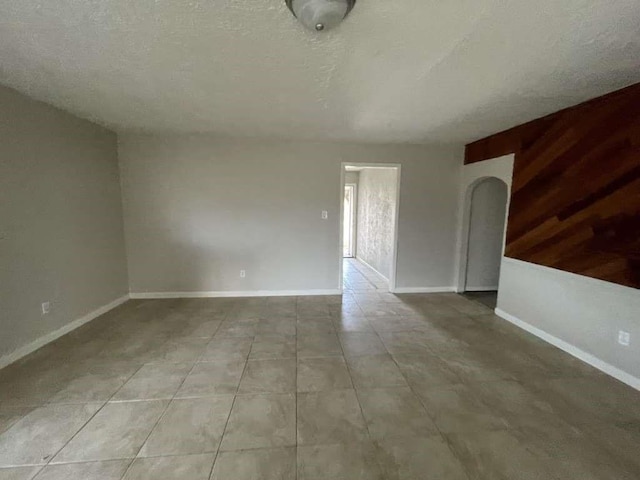 tiled spare room featuring wood walls