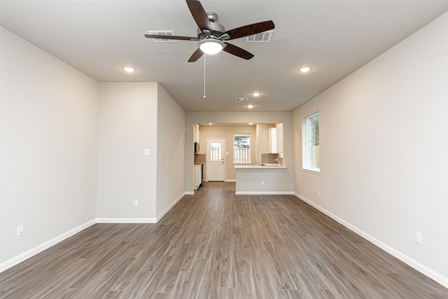 unfurnished living room featuring dark wood-type flooring and ceiling fan