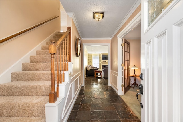 foyer entrance with ornamental molding and a textured ceiling