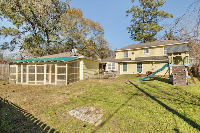 back of property featuring a playground, a deck, a sunroom, and a lawn