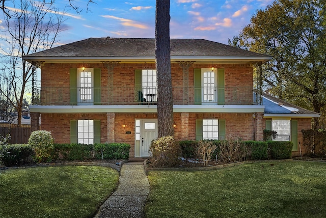 view of front of house featuring a porch, a balcony, and a yard