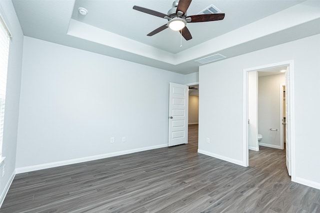 unfurnished bedroom with dark wood-type flooring, ceiling fan, and a raised ceiling